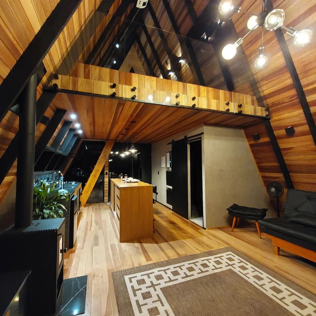 Interior do chalé modelo A com mezanino, iluminação e cozinha integrada